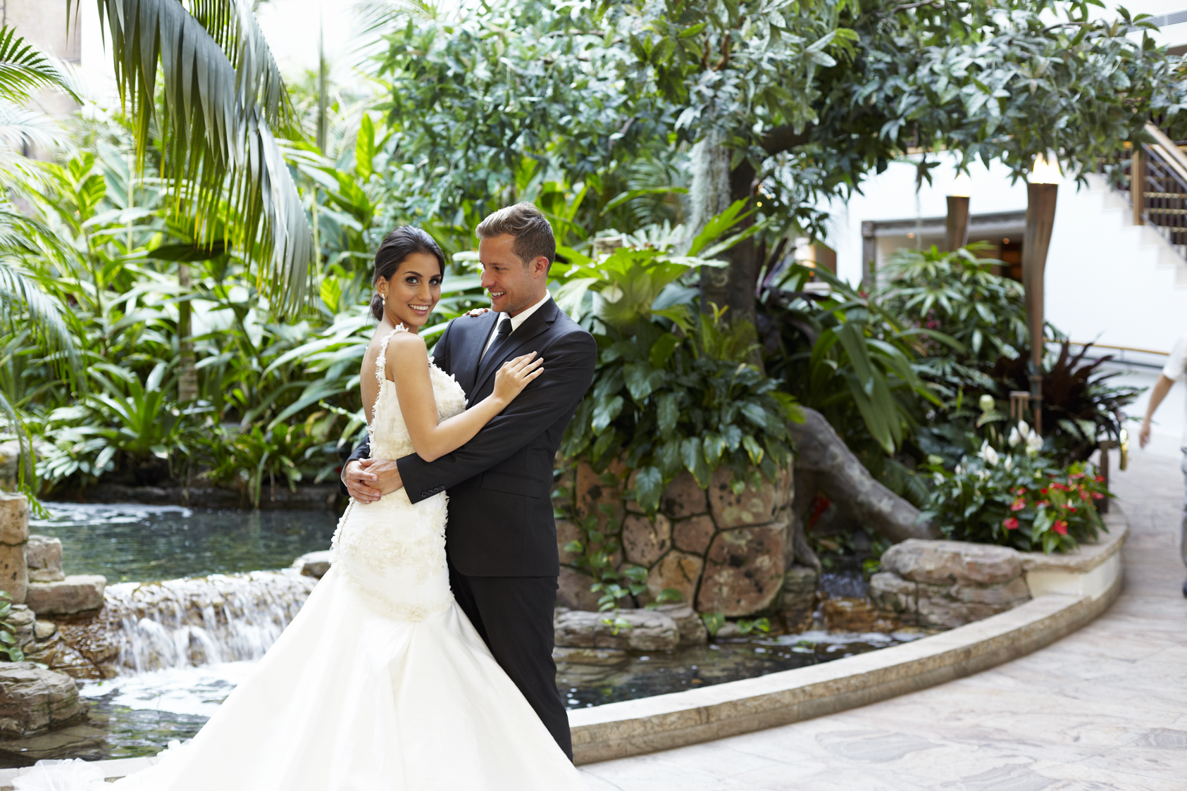 Happy wedding couple posing in front of indoor waterwall