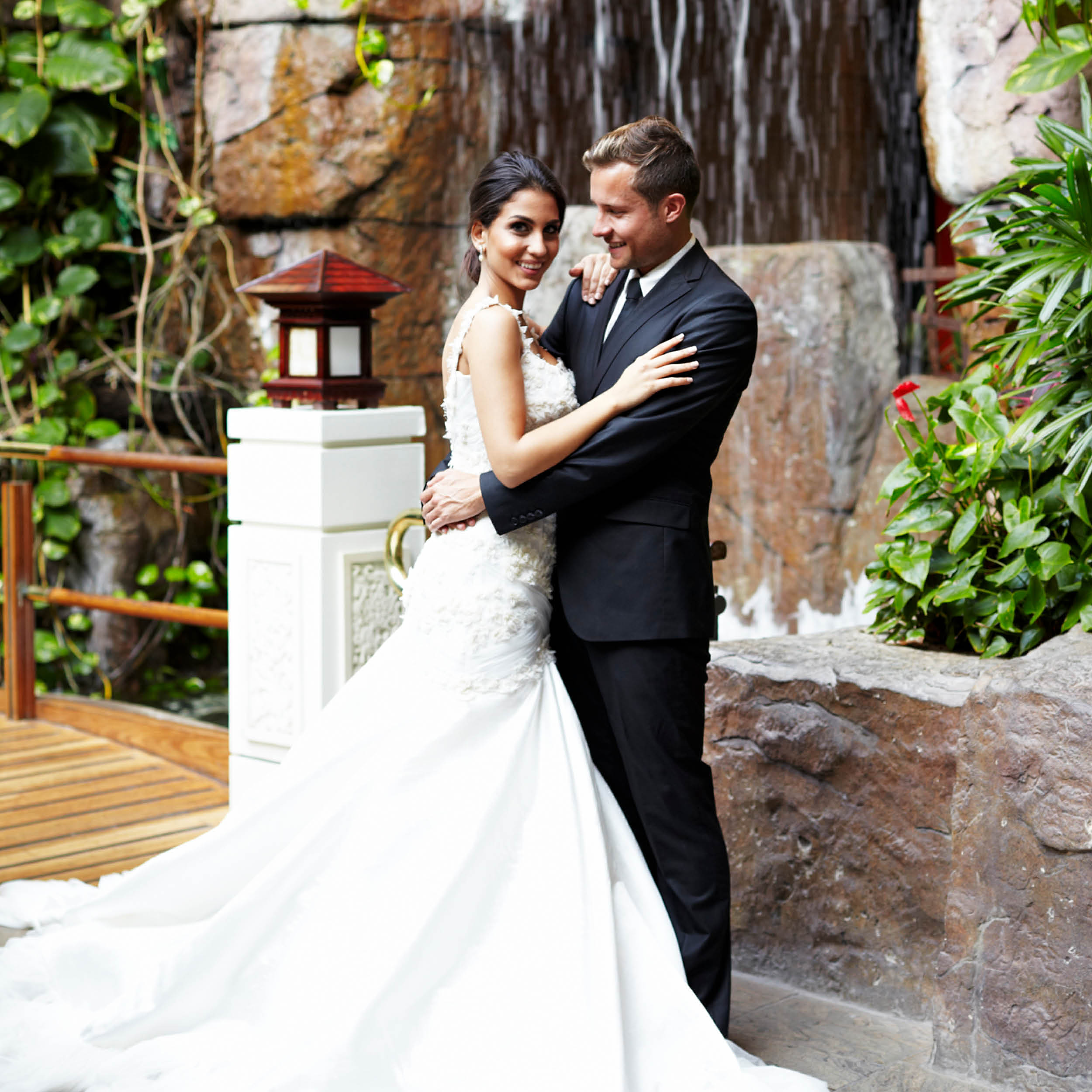 Happy wedding couple posing in front of water fountain